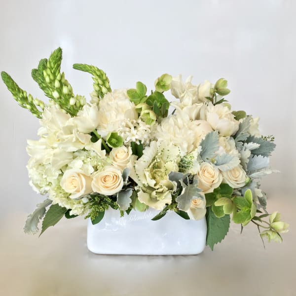 Low white and cream flower arrangement with roses in a rectangular white vase