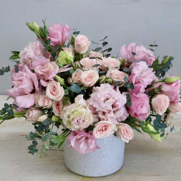 Low pink and blush flower arrangement in a white ceramic pot