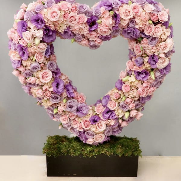 Large open heart of pink and purple flowers on a moss-covered rectangular base