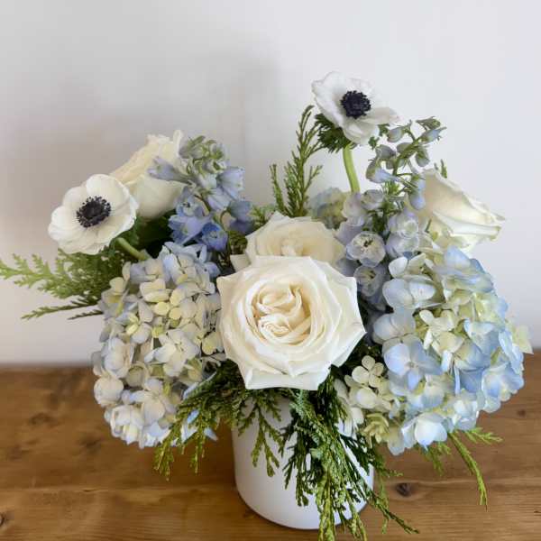 White roses and blue hydrangeas in a white vase