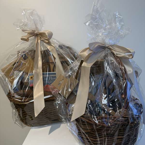 Two wrapped gift baskets with satin bows and books inside