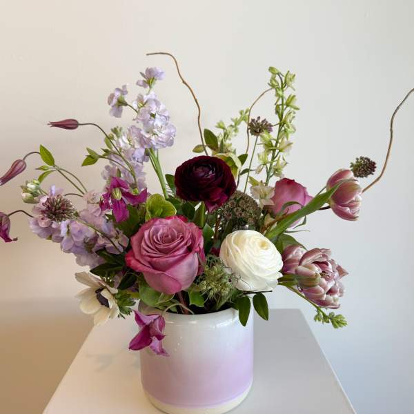 Mixed pink, white, and lavender flowers in a white vase