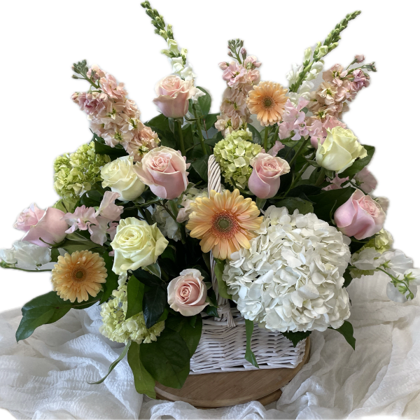 Pastel roses, gerbera daisies, and hydrangeas in a white basket