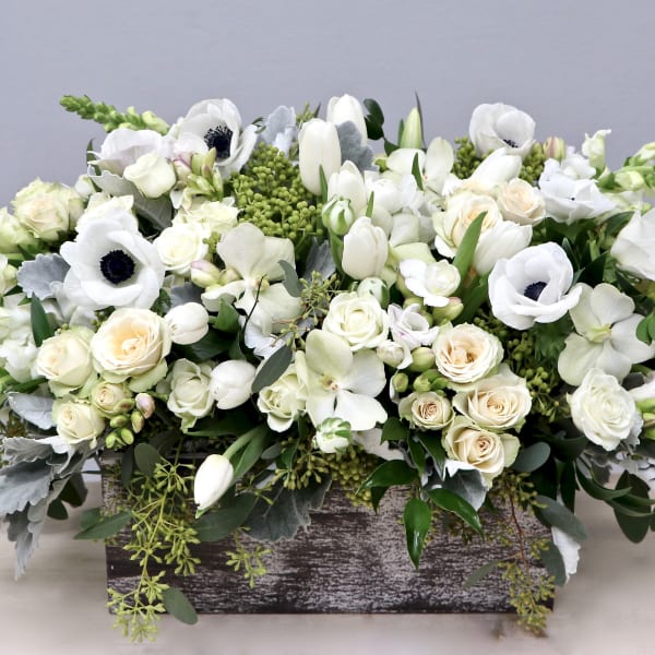 Low arrangement of white and cream flowers in a rustic wooden box