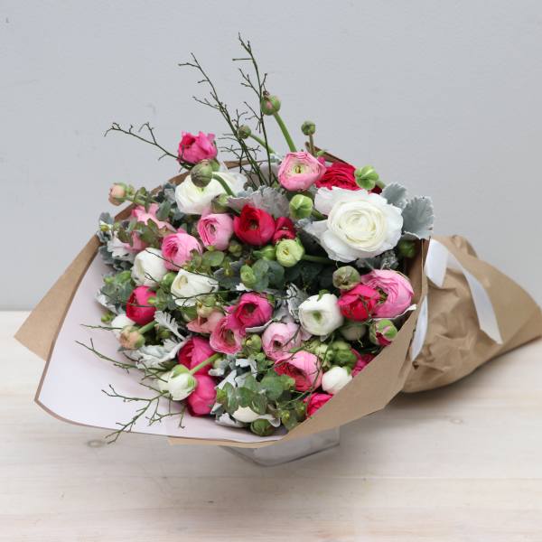 Bouquet of pink, white, and red ranunculus wrapped in brown paper