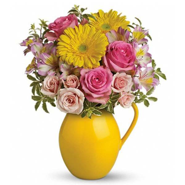 Yellow and pink mixed flower arrangement with roses and gerbera daisies in a bright yellow pitcher
