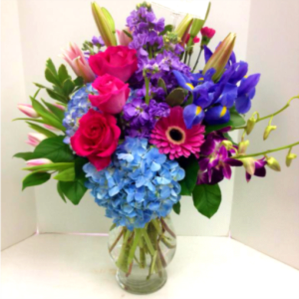 Colorful bouquet of roses, hydrangeas, irises, and orchids in a glass vase