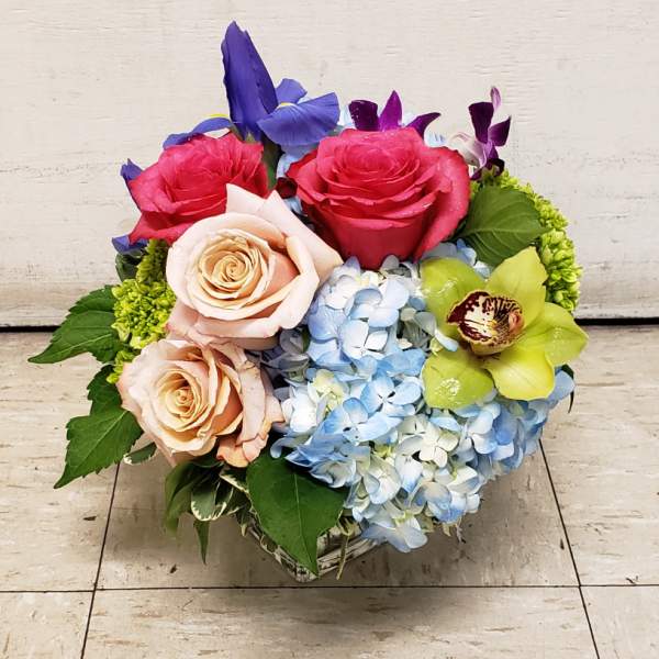 Bouquet of roses, hydrangeas, and orchids in a low square vase