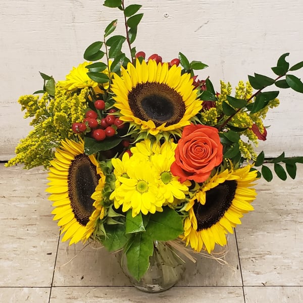 Sunflower and orange rose arrangement in a glass vase