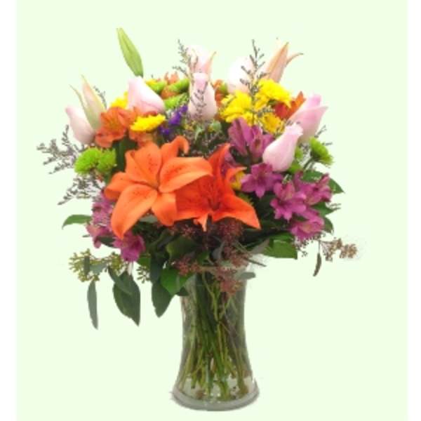 Mixed bouquet of lilies and colorful flowers in a clear glass vase