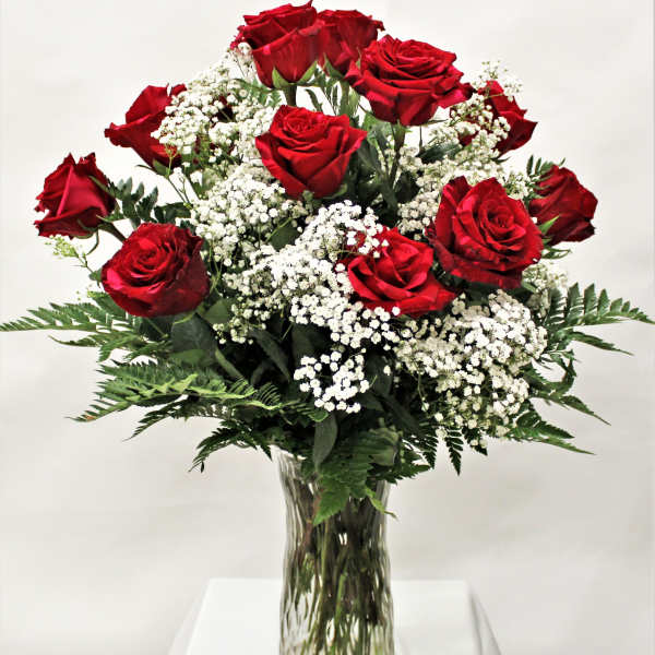 Arrangement of red roses with white filler flowers in a clear glass vase