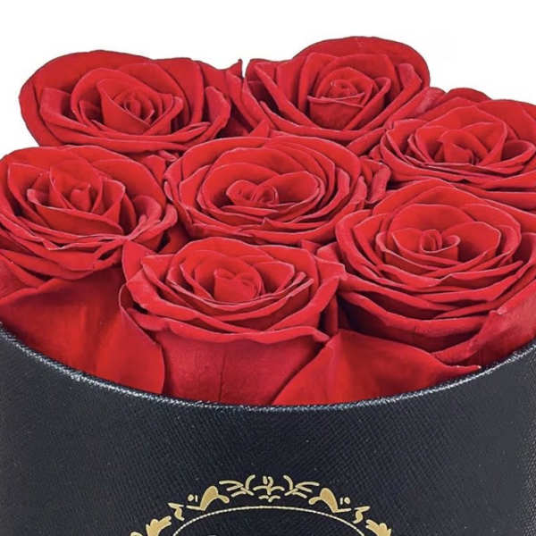 Round black hatbox filled with tightly packed red roses viewed from above