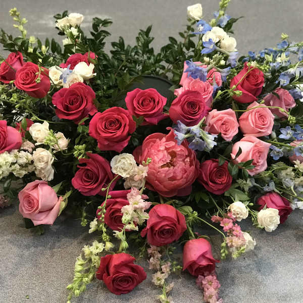 Loose floral arrangement of pink and red roses with blue accents