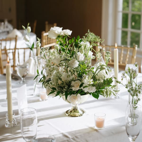 White floral centerpiece on a banquet table with candles