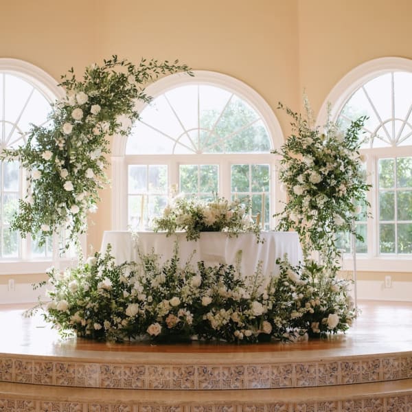 White floral wedding ceremony decor with greenery on a stage