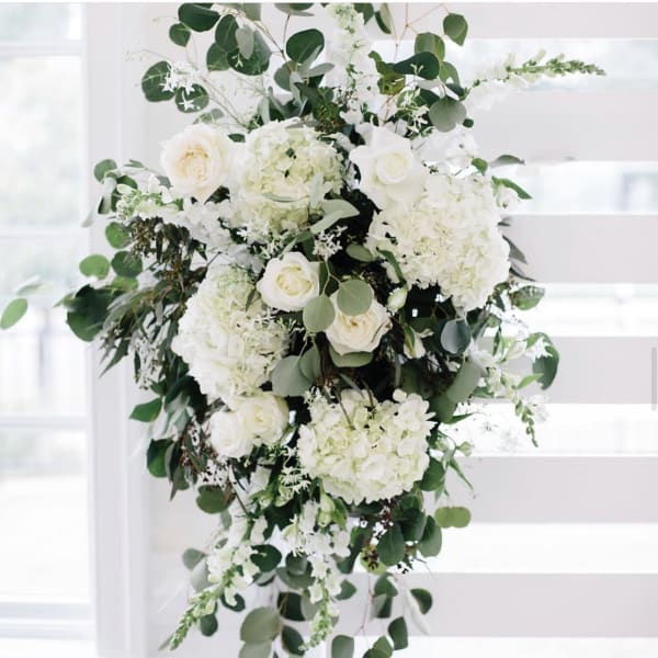Tall white floral arrangement with roses and hydrangeas