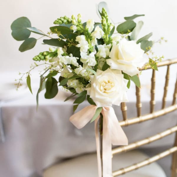 White rose bouquet with greenery and a pale ribbon