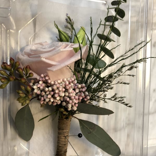 Single pale pink rose boutonniere with greenery and berries in a clear box