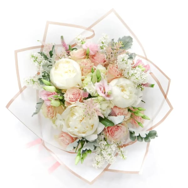 Bouquet of blush and white flowers wrapped in clear paper
