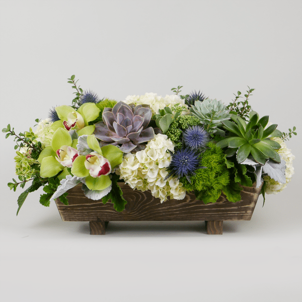 Succulents and orchids arranged in a wooden planter box