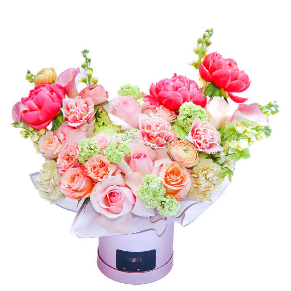 Bouquet of pink and peach flowers in a round hatbox