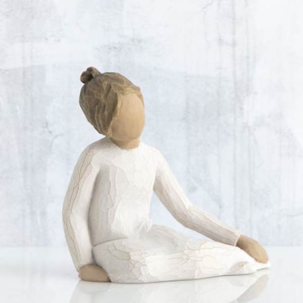 Seated figurine of a girl in a white dress with a bun hairstyle