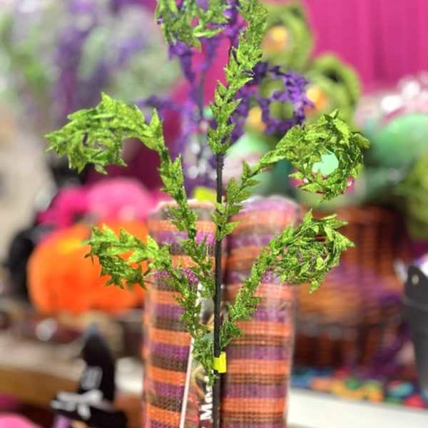 Green glittery decorative stems in a striped vase