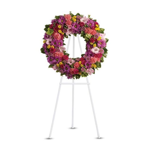 Bright pink and purple standing floral wreath on a white easel