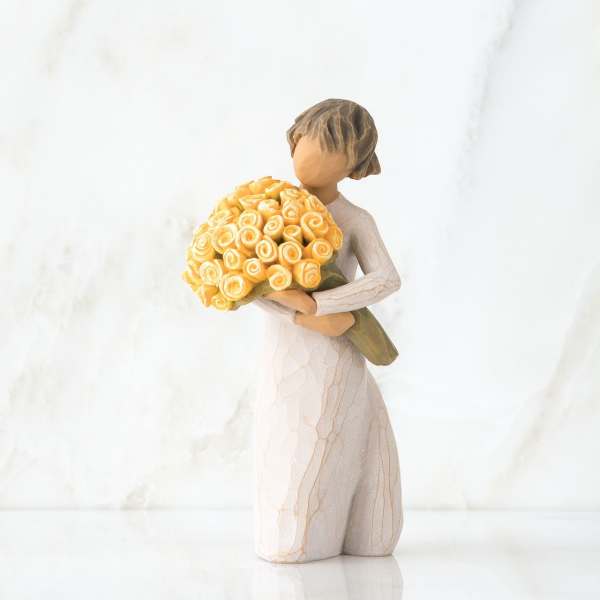 Kneeling figurine holding a large yellow rose bouquet against a light background