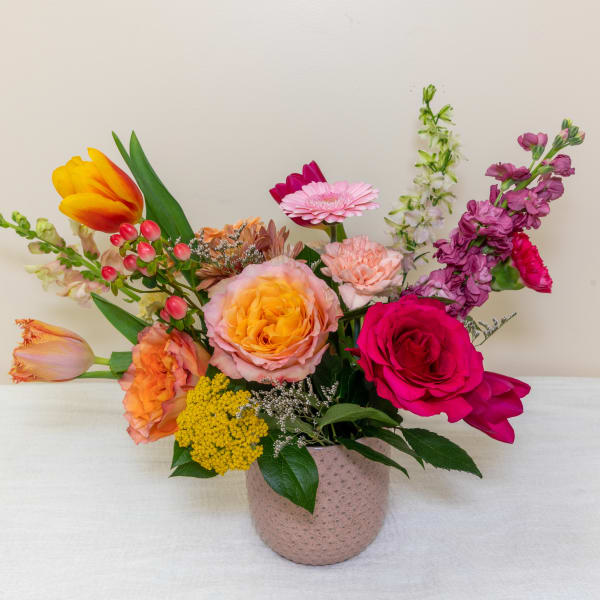 Mixed bouquet in a pink textured vase with roses, tulips, and gerbera daisies