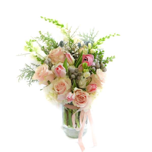 Pink and cream rose bouquet in a glass vase with a ribbon