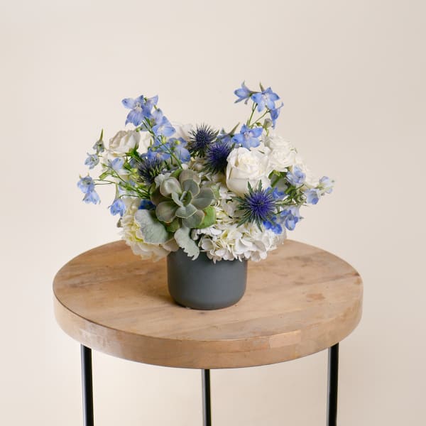 Blue and white floral arrangement in a dark vase on a wooden table