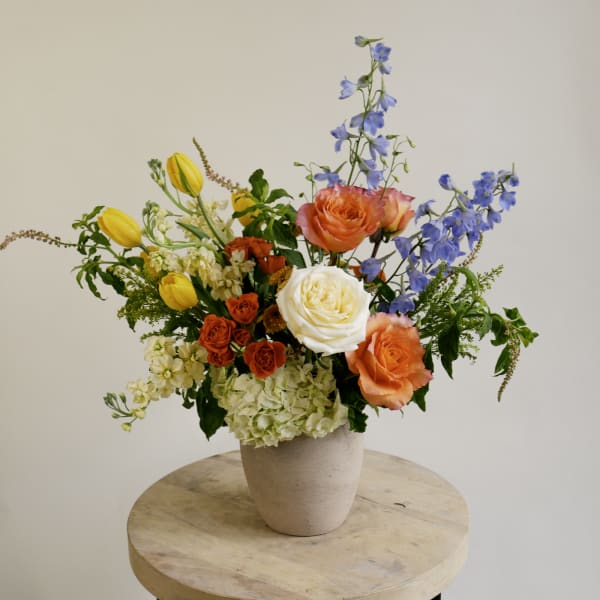 Colorful mixed flower arrangement in a beige vase