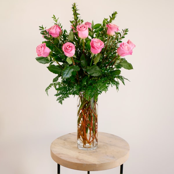 Pink roses arranged in a clear glass vase on a round table