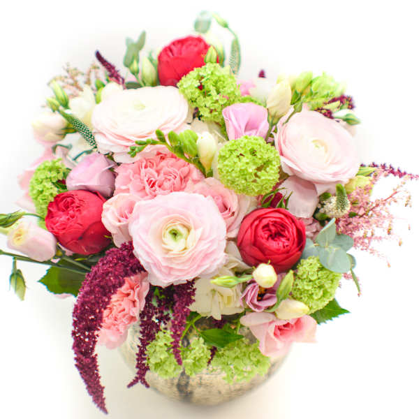 Mixed pink and red flowers arranged in a round vase