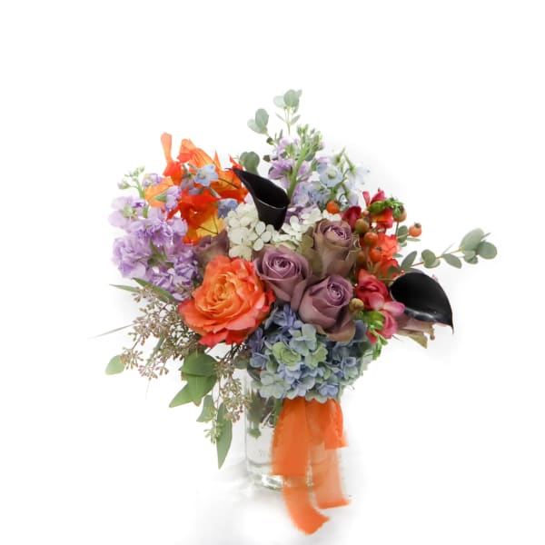 Colorful bouquet of roses, hydrangeas, and mixed blooms in a glass vase