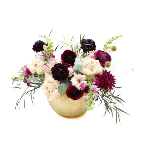 Mixed bouquet of cream, burgundy, and pink flowers in a gold vase