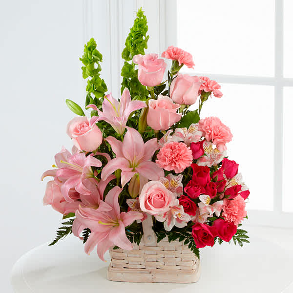 Pink lilies and roses arranged in a wicker basket