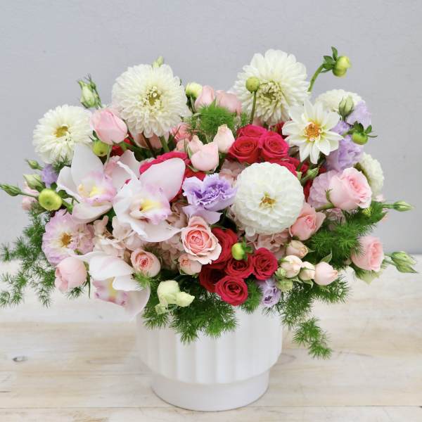 Mixed bouquet of pink, white, and red flowers in a white vase