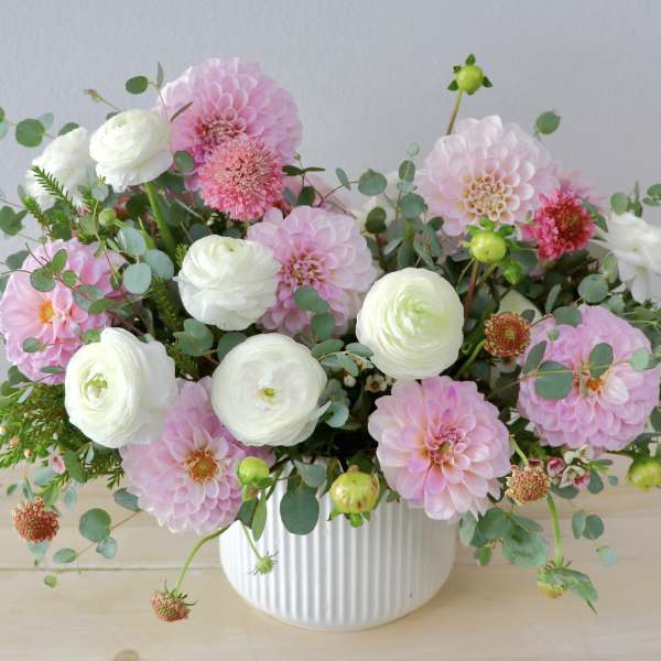 Pink and white flowers arranged in a white ribbed vase