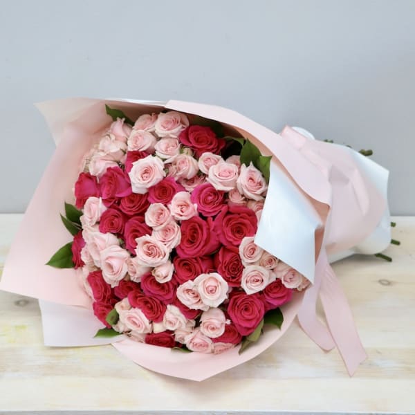 Large bouquet of light and hot pink roses wrapped in pale pink and white paper with ribbon