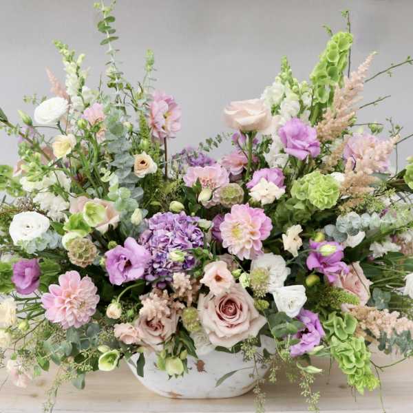 Large pastel floral arrangement in a white bowl vase