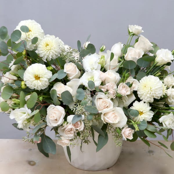 Large white and cream flower arrangement in a white ceramic vase