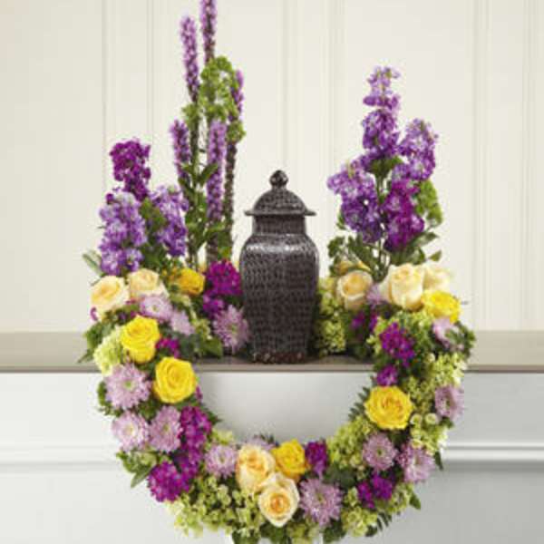 Floral wreath with purple, yellow, and pink flowers around a black urn