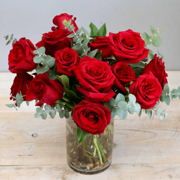 Arrangement of red roses with eucalyptus in a clear glass vase