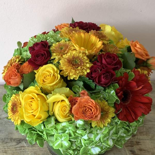 Mixed bouquet of roses, gerbera daisies, and chrysanthemums in a glass vase