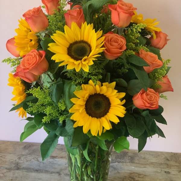 Sunflower and peach rose bouquet in a clear glass vase