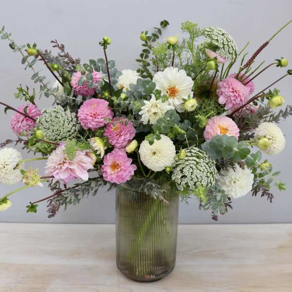 Tall glass vase arrangement of pink and white dahlias with airy filler flowers