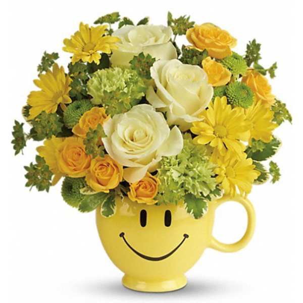 Yellow and white roses and daisies arranged in a yellow smiley-face mug