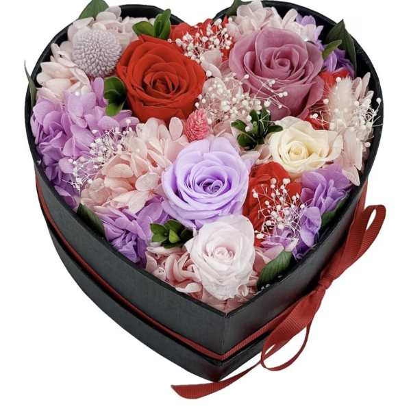Heart-shaped black box filled with red, pink, lavender, and white roses and mixed blooms